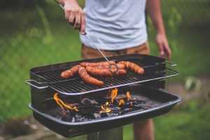BBQ kok bereidt voedsel op locatie voor gezellige barbecue met vrienden en familie